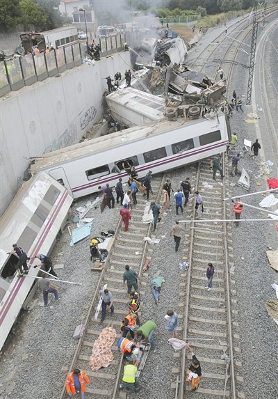 24日，救援人員在西班牙列車脫軌現場。一節車廂被強大的慣性拋上鐵道邊的高臺。