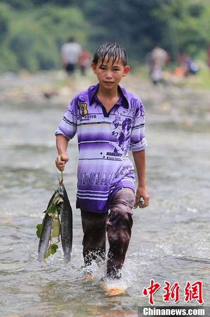 圖為7月9日，一名男孩在鬧魚節(jié)活動(dòng)中抓到了兩條魚。譚凱興 攝