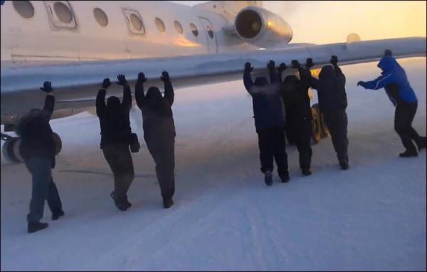 伊加爾市一架客機起飛前被凍在了跑道上。飛機上的乘客不得不下來推飛機。