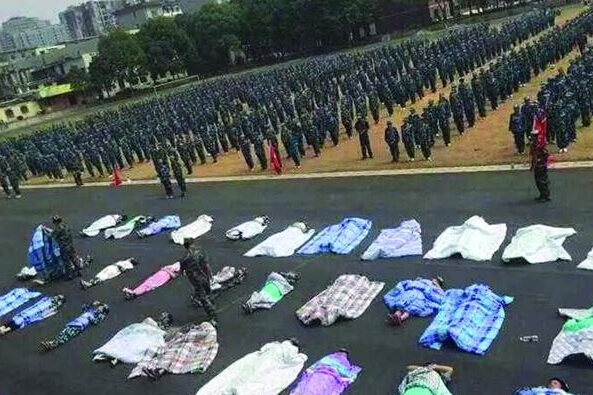 20多名女生躺在瀝青跑道上，身上嚴嚴實實地裹著棉被，接受太陽的照曬。