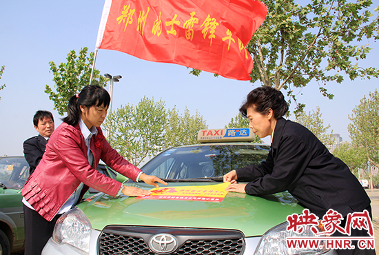 　　授旗結束后，首都的士雷鋒車隊王鳳進隊長（右）與鄭州的的哥的姐在車身上貼上標識。