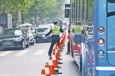 省人民醫(yī)院南門(mén)的路中間擺放反光錐，交警示意由西向東車(chē)輛從前方繞行。