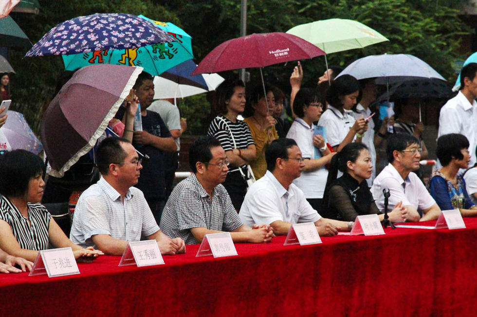 在主席臺上觀看的校領導也堅持不打傘陪學生一起淋雨，身旁站滿了打傘觀看的家長。