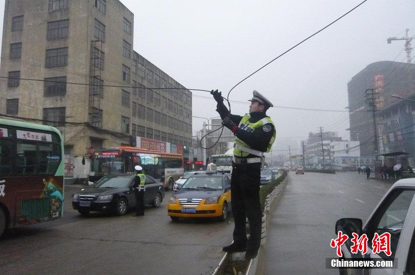 安徽一交警雨中托舉電纜讓車輛通過